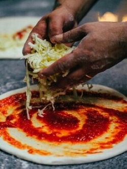 pizza wordt bereid, er wordt kaas op gelegd